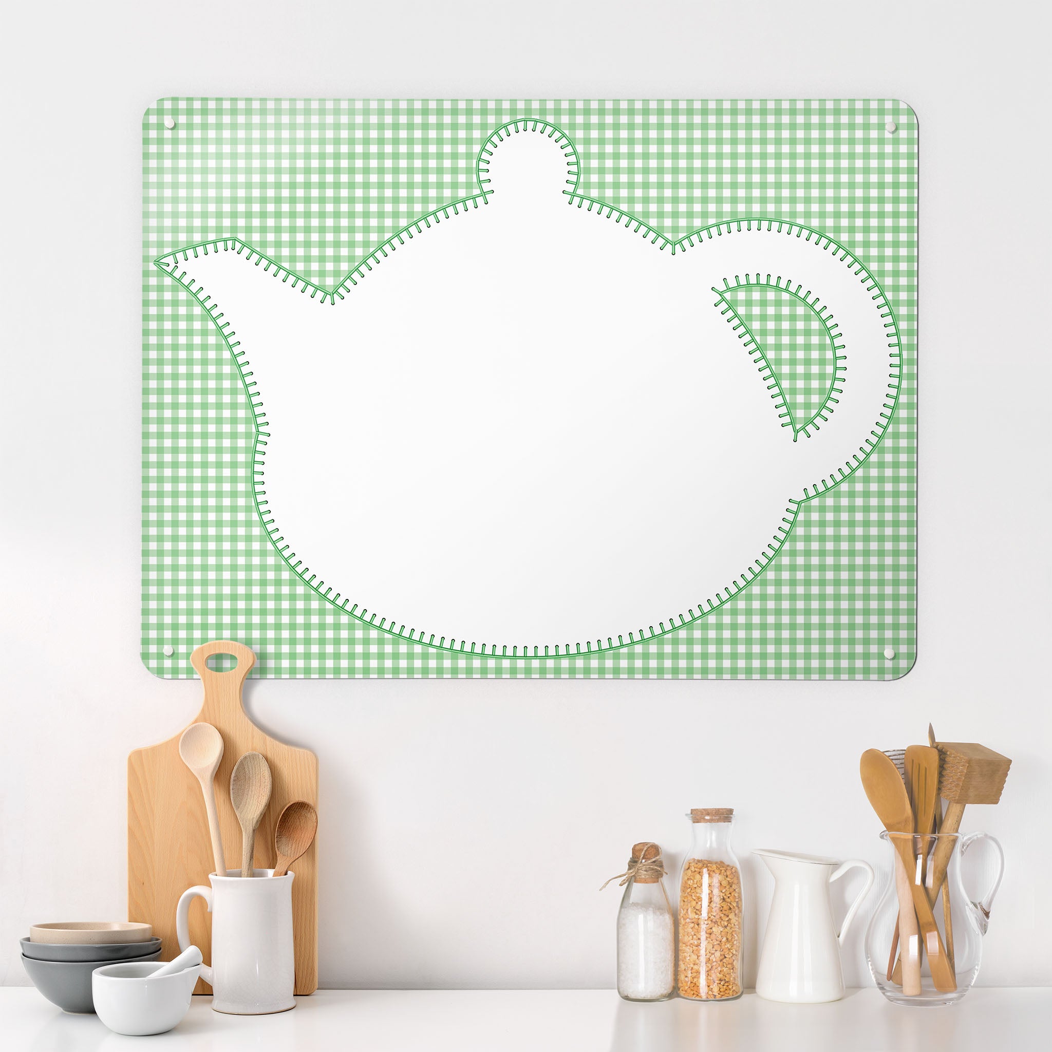 A  kitchen interior with a magnetic metal wall art panel showing an appliqué teapot design in white on a green gingham background