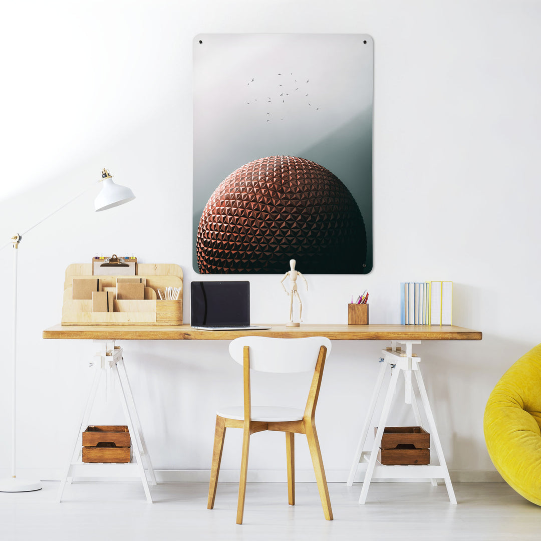 A desk in a workspace setting in a white interior with a magnetic metal wall art panel showing the Epcot Centre in Disney World