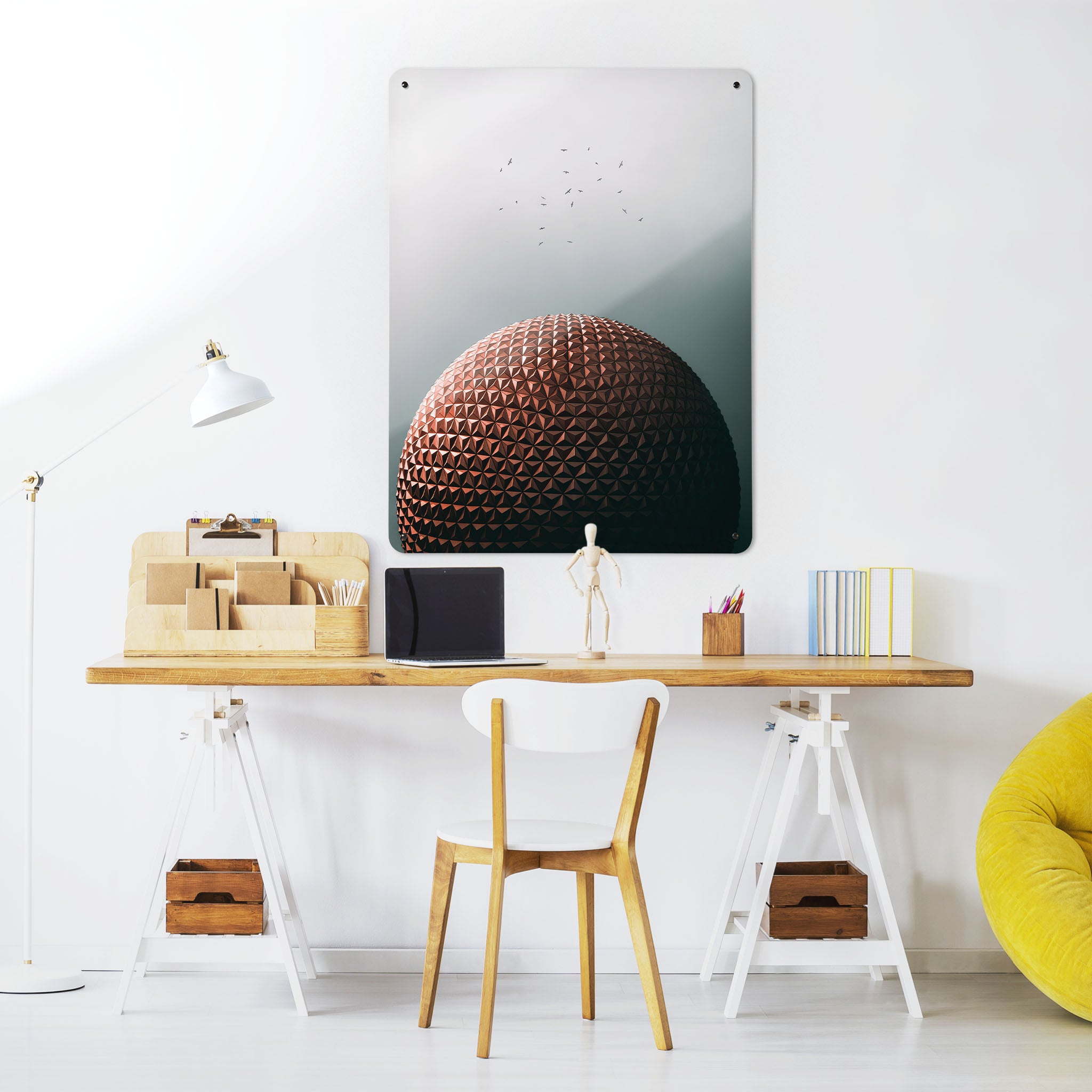 A desk in a workspace setting in a white interior with a magnetic metal wall art panel showing the Epcot Centre in Disney World