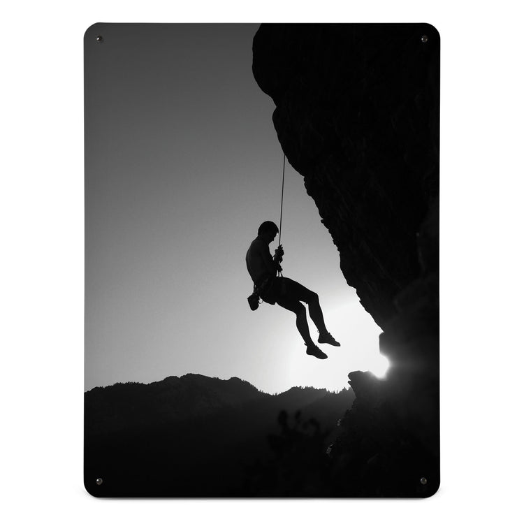 A large magnetic notice board by Beyond the Fridge with a black and white photographic image of a rock climber suspended on a cliff in silhouette