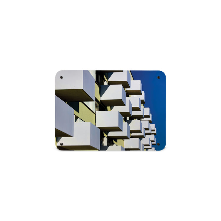 A small magnetic notice board by Beyond the Fridge with an image of brutalist balconies and a blue sky