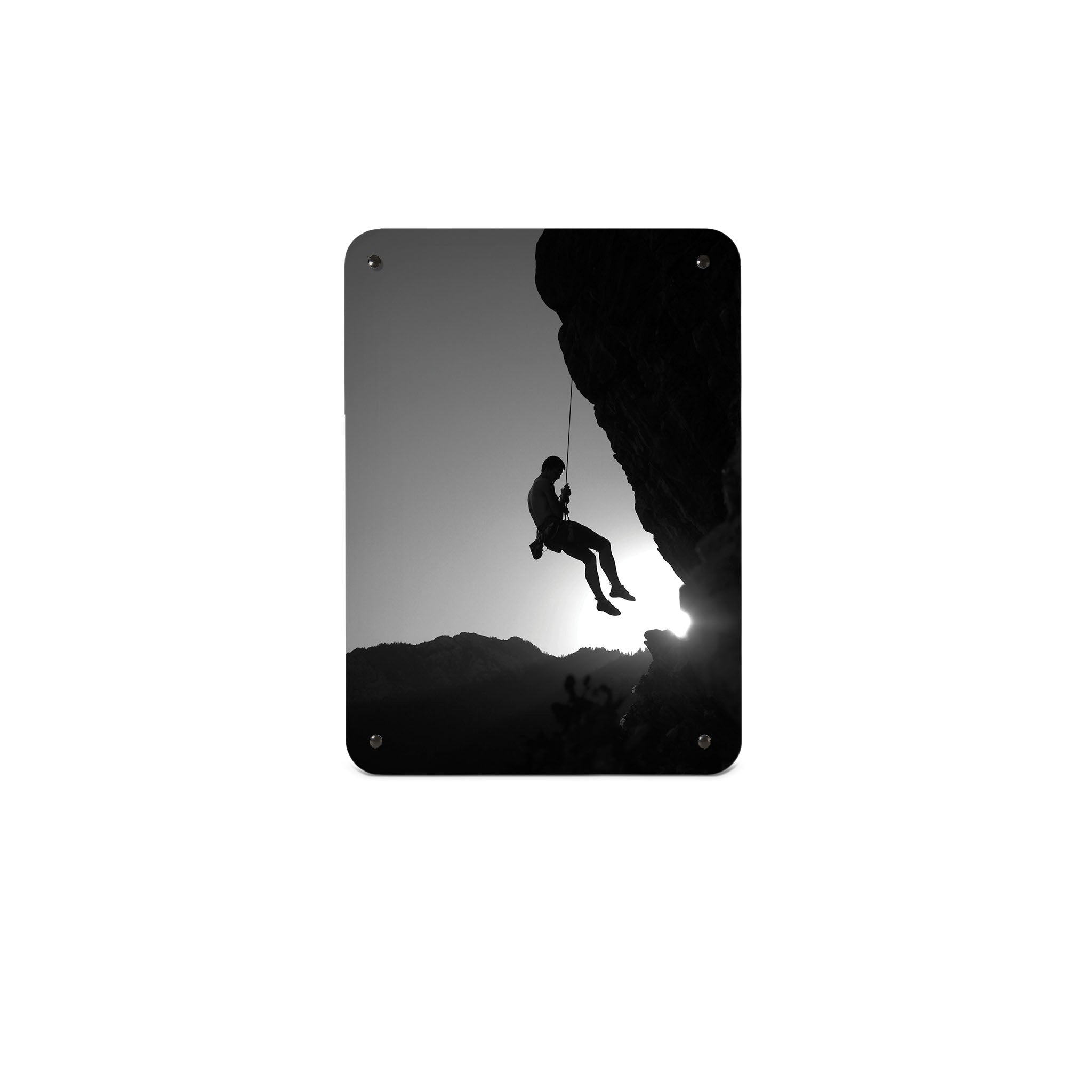 A small magnetic notice board by Beyond the Fridge with a black and white photographic image of a rock climber suspended on a cliff in silhouette
