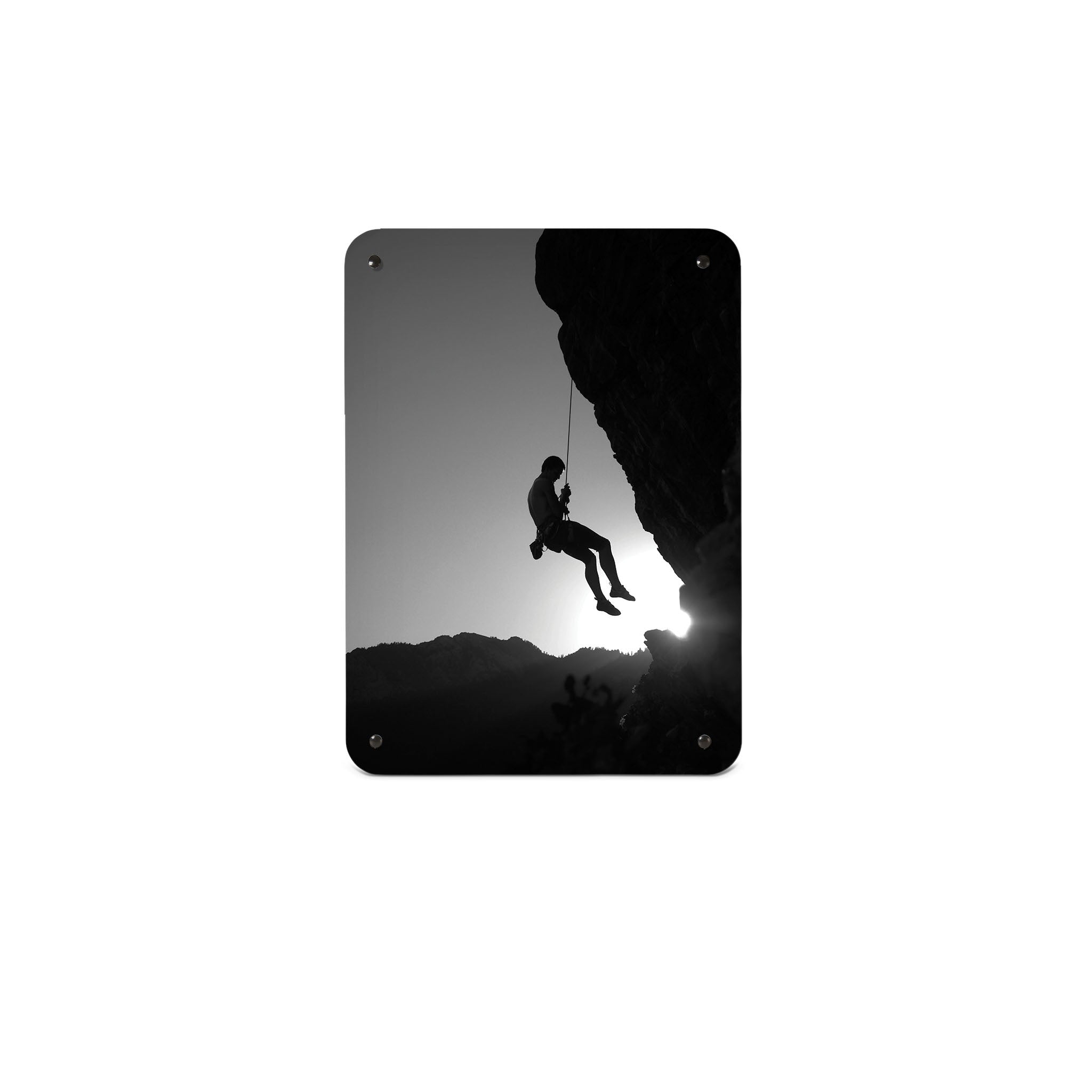 A small magnetic notice board by Beyond the Fridge with a black and white photographic image of a rock climber suspended on a cliff in silhouette 