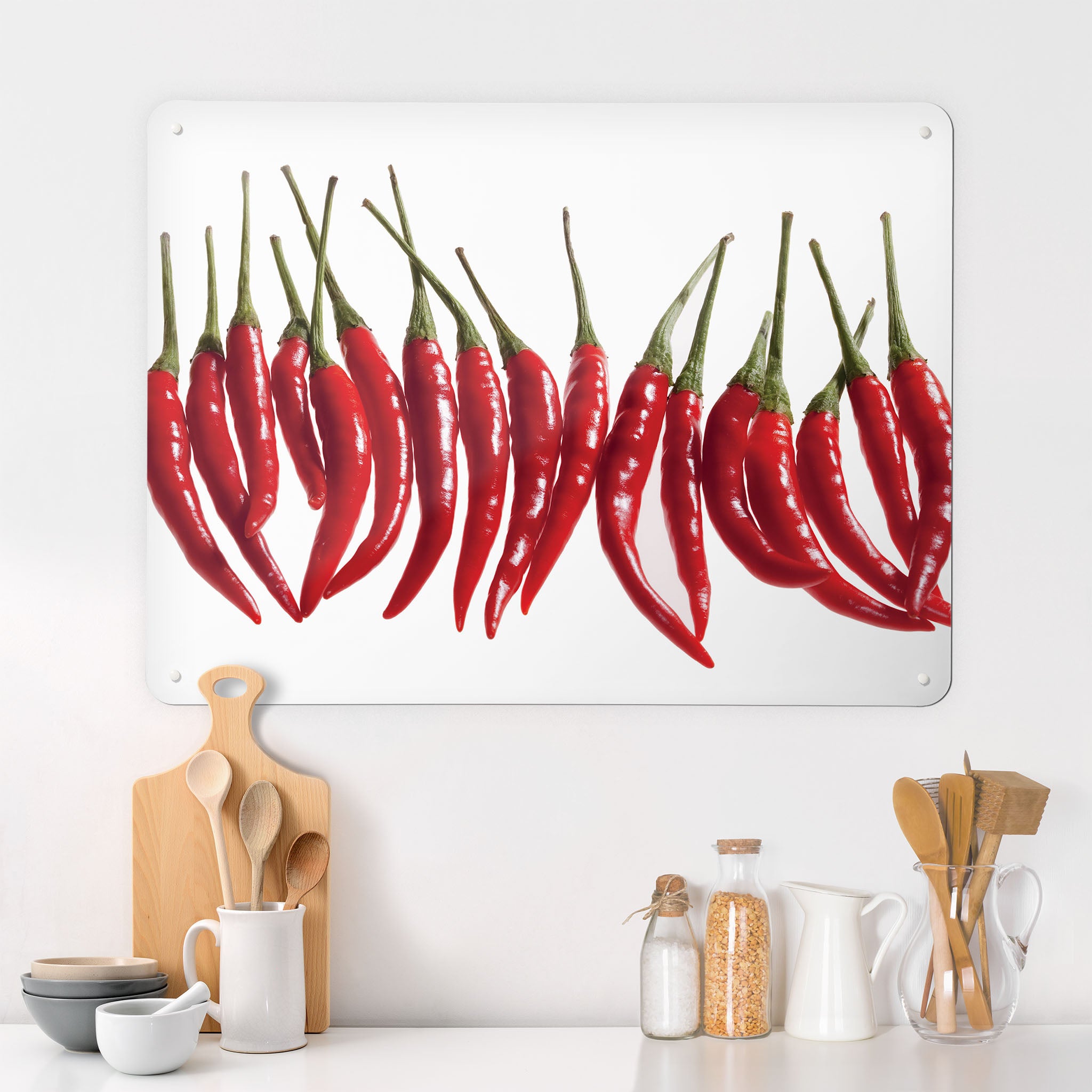 A kitchen interior with a magnetic metal wall art panel showing a photograph of a line of red chillies