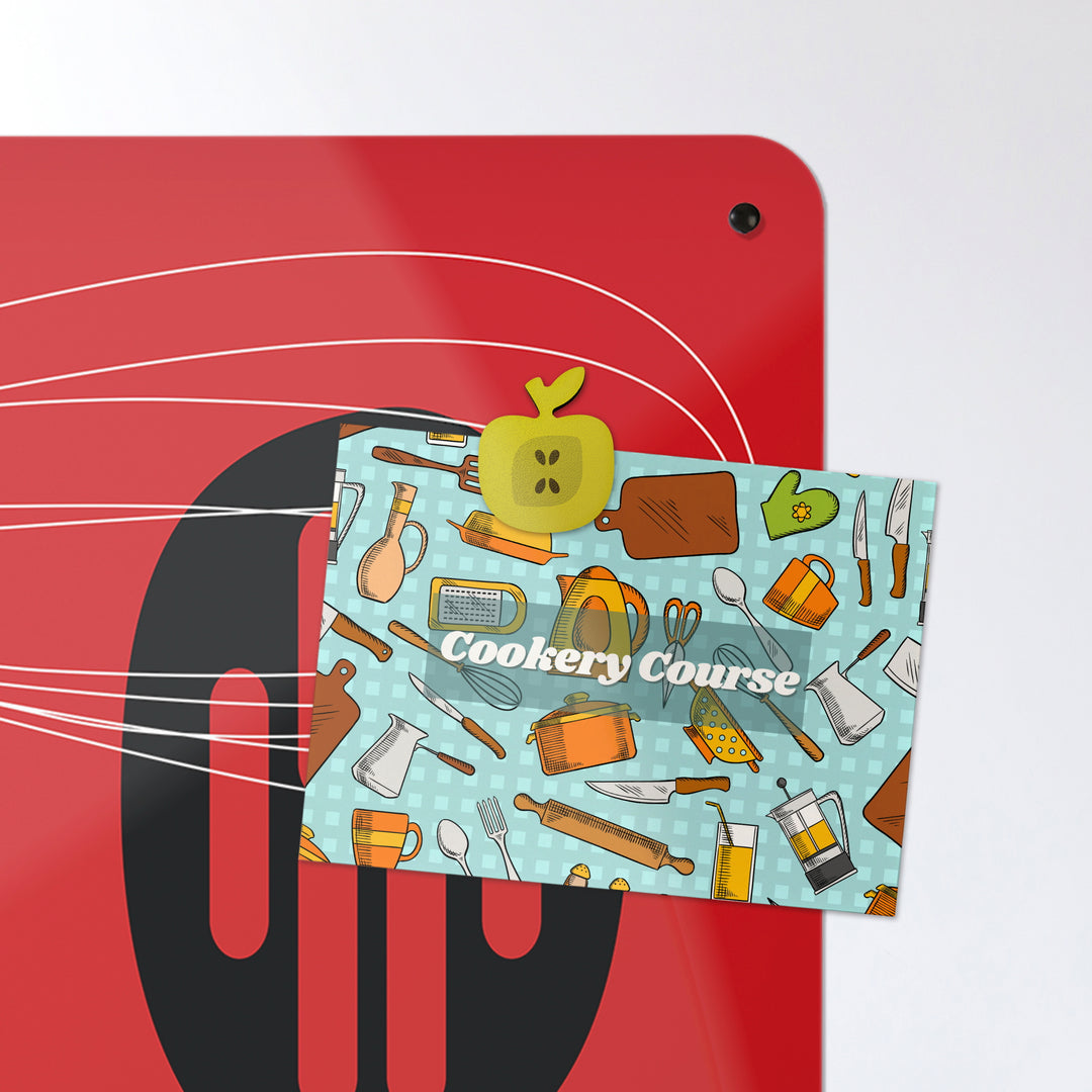 A postcard attached with an apple shaped fridge magnet on a red utensils design magnetic board or metal wall art panel