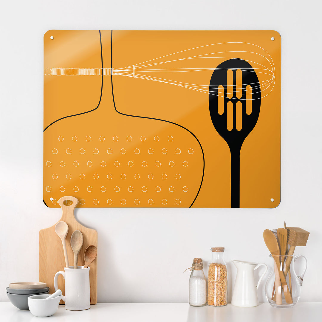 A kitchen interior with a magnetic metal wall art panel showing a orange utensils design