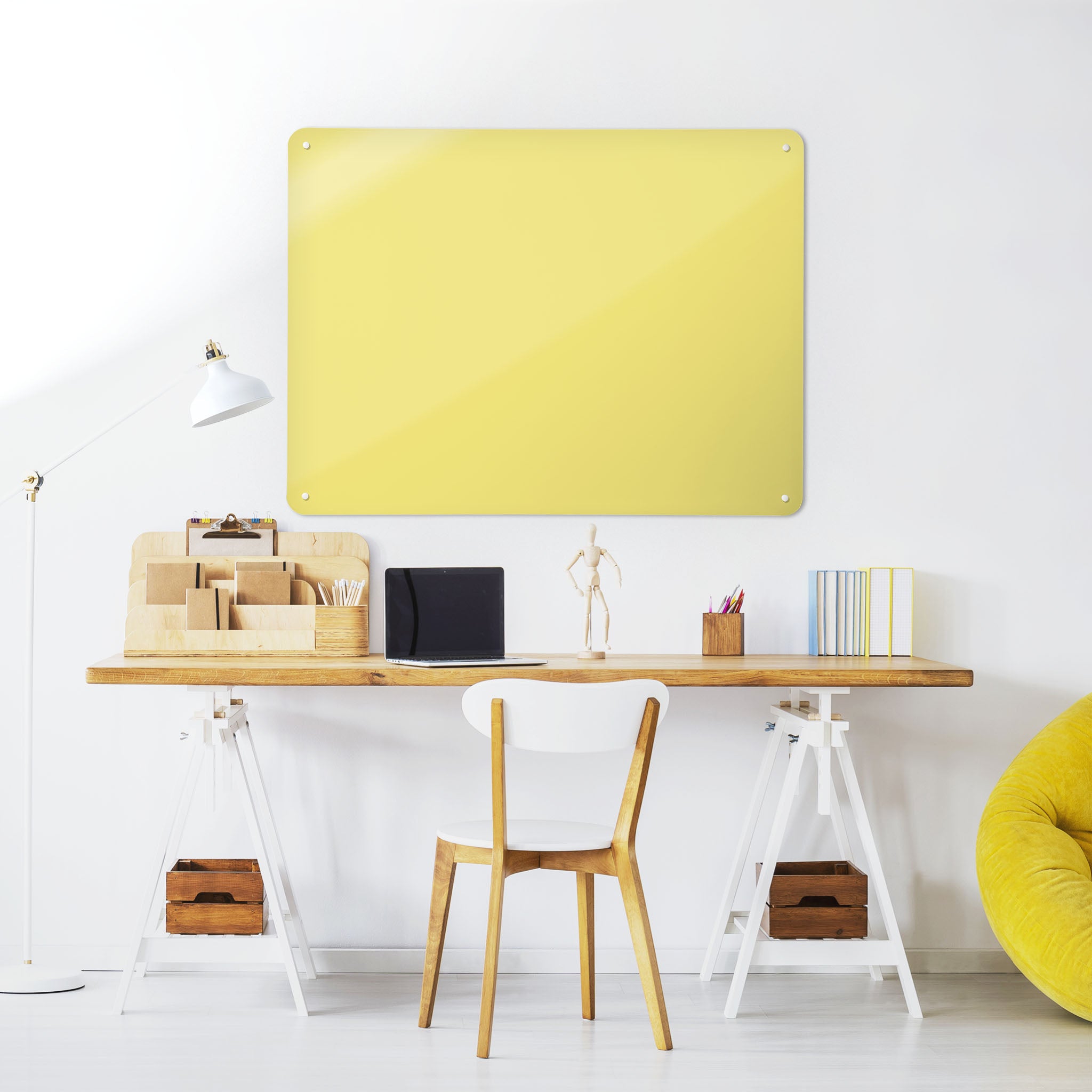 A desk in a workspace setting in a white interior with a plain yellow coloured magnetic metal wall art panel