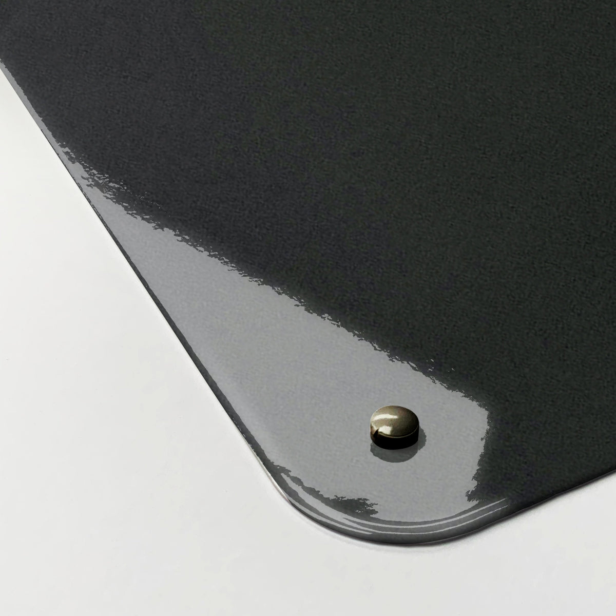 Close-up of the corner of the Balancing Stones magnetic notice board, showing the gloss finish and a screw cap
