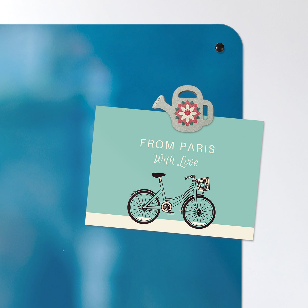 A postcard held by a fridge magnet on the Bicycle And Flower Basket magnetic notice board