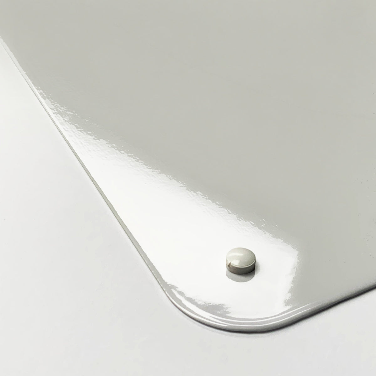 Close-up of the corner of the Cherry magnetic notice board in Cherry, showing the gloss finish and a screw cap