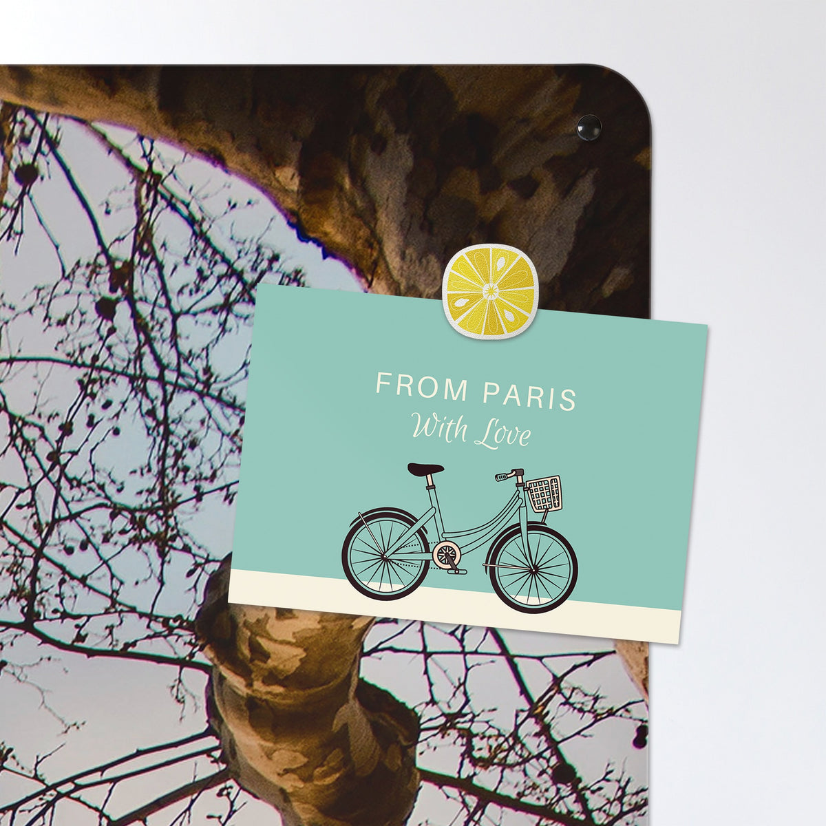 A postcard held by a fridge magnet on the Eiffel Tower magnetic notice board