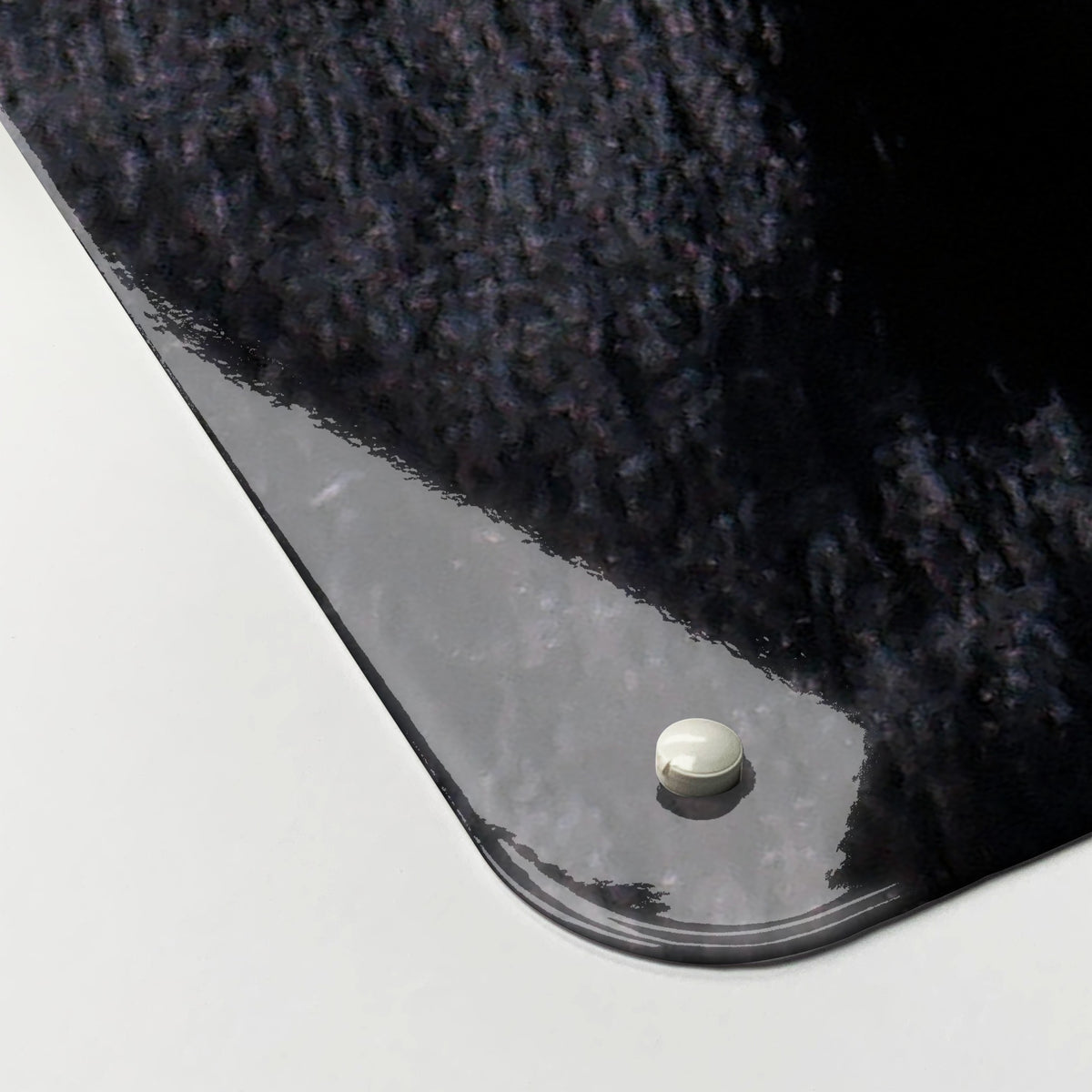 Close-up of the corner of the Friesian Cow magnetic notice board, showing the gloss finish and a screw cap