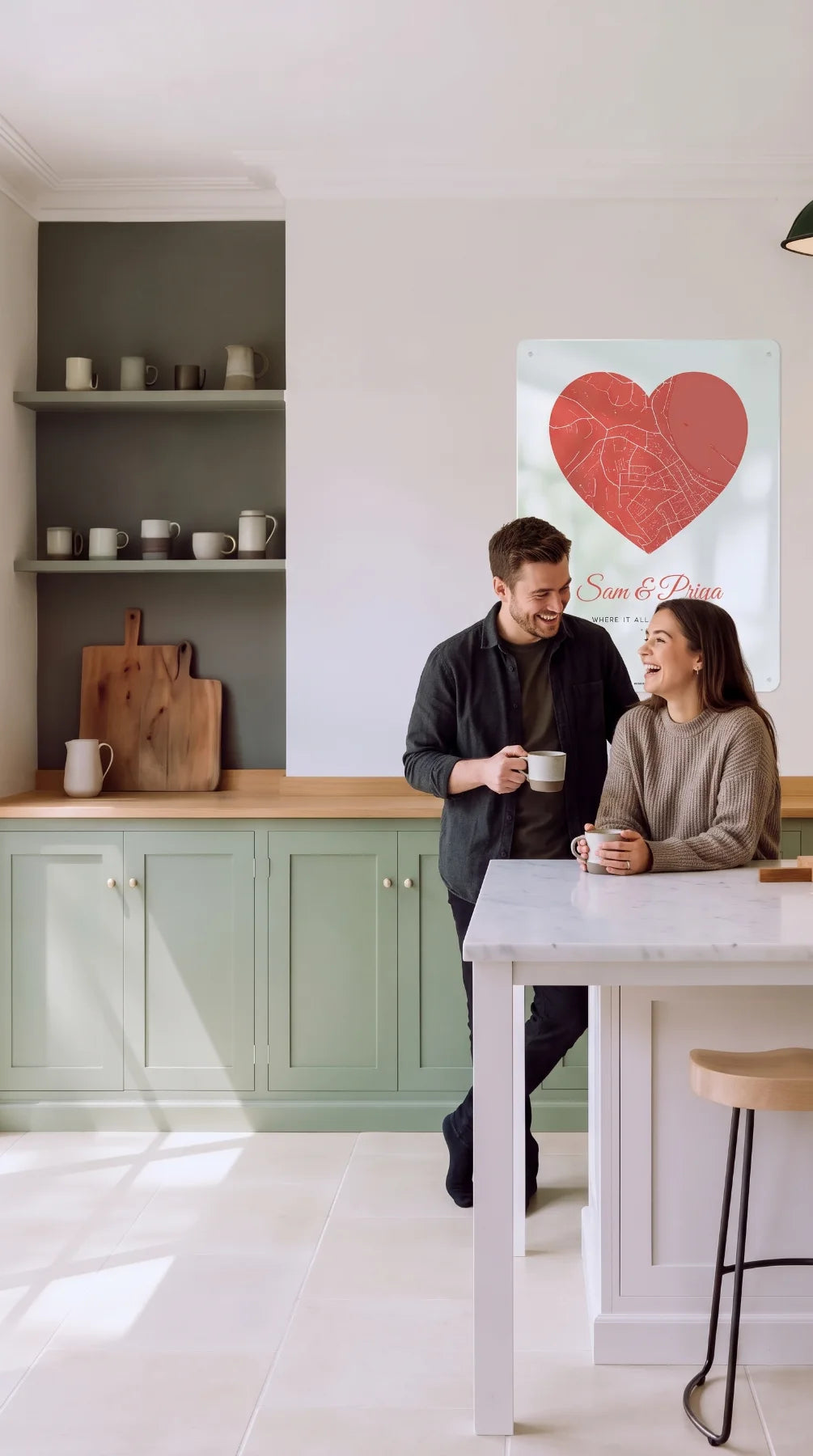 A couple laughing at a kitchen island beneath a heart street map board reading Sam & Priya