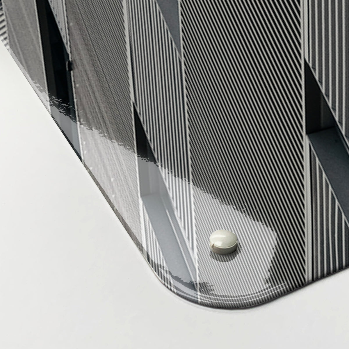 Close-up of the corner of the London Skyscraper magnetic notice board, showing the gloss finish and a screw cap