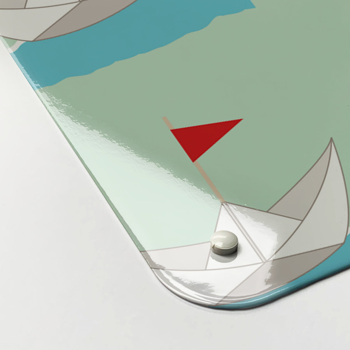 Close-up of the corner of the Paper Boats magnetic notice board in Paper Boats, showing the gloss finish and a screw cap