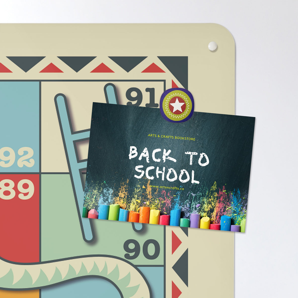 A postcard held by a fridge magnet on the Snakes And Ladders magnetic notice board in Snakes and Ladders