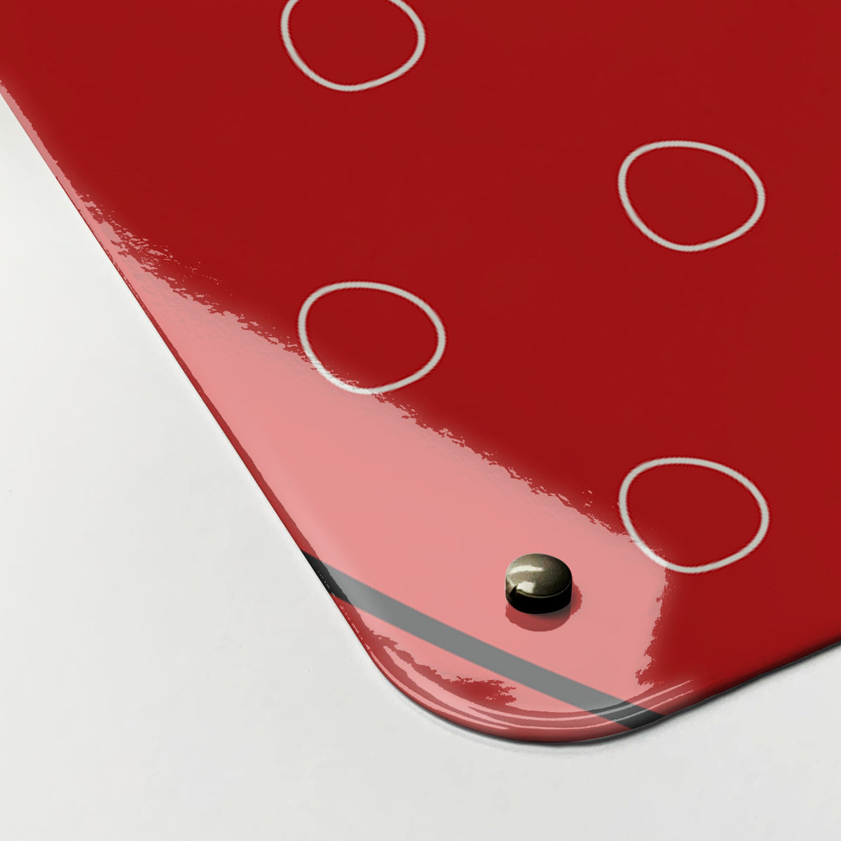 Close-up of the corner of the Utensils magnetic notice board in red, showing the gloss finish and a screw cap