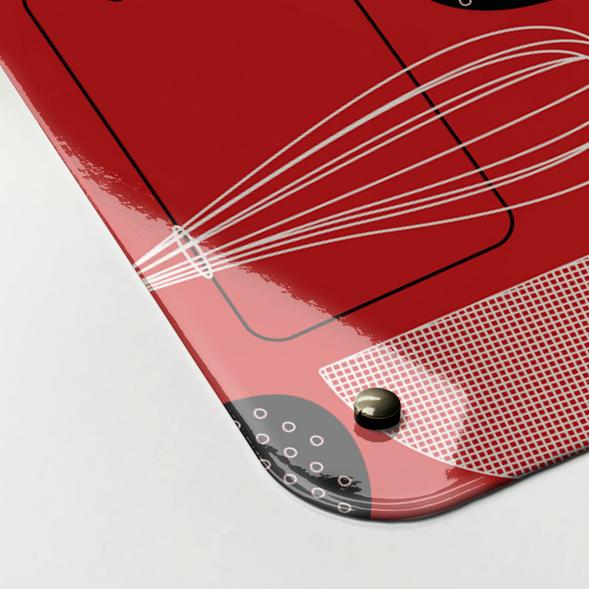 Close-up of the corner of the Utensils Repeat Pattern magnetic notice board in Red, showing the gloss finish and a screw cap