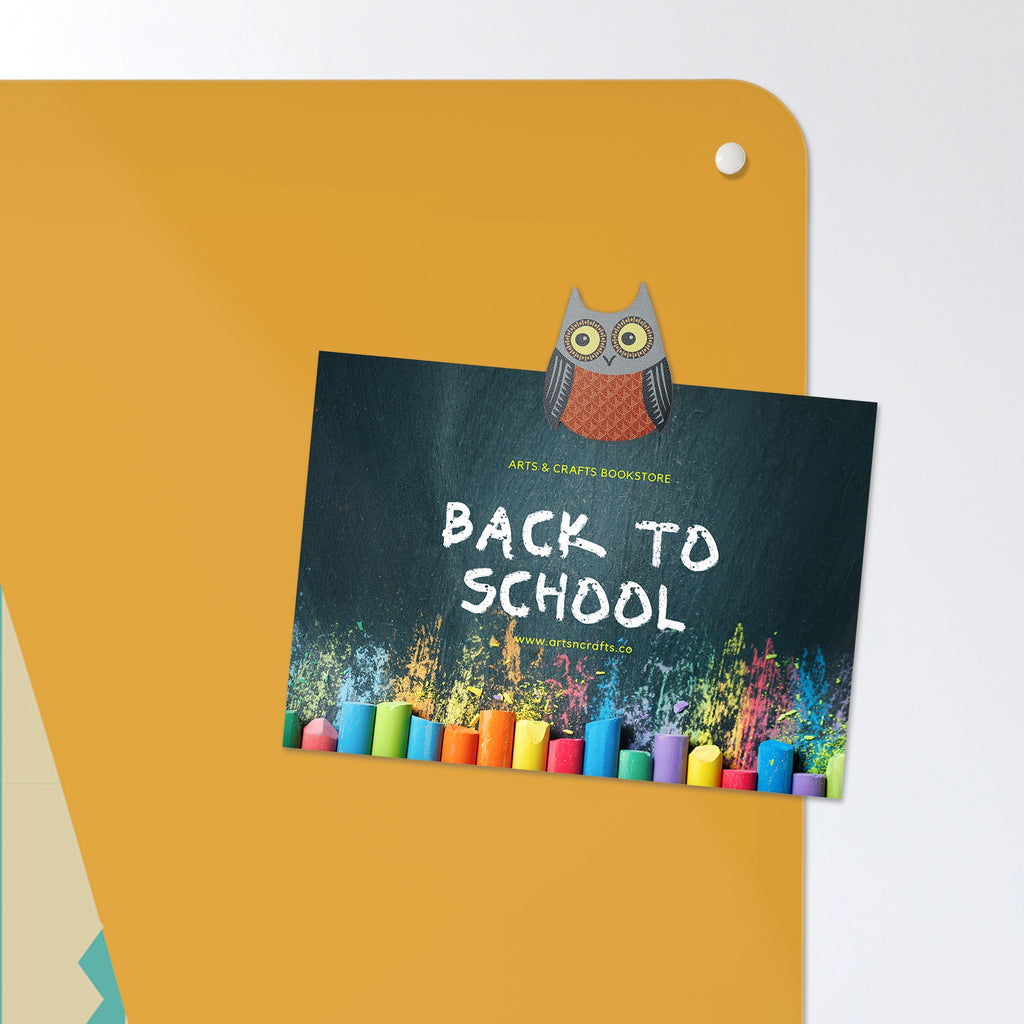 A postcard held by a fridge magnet on the Wise Owl Times Tables magnetic notice board in 'Wise Owl - Times Tables'