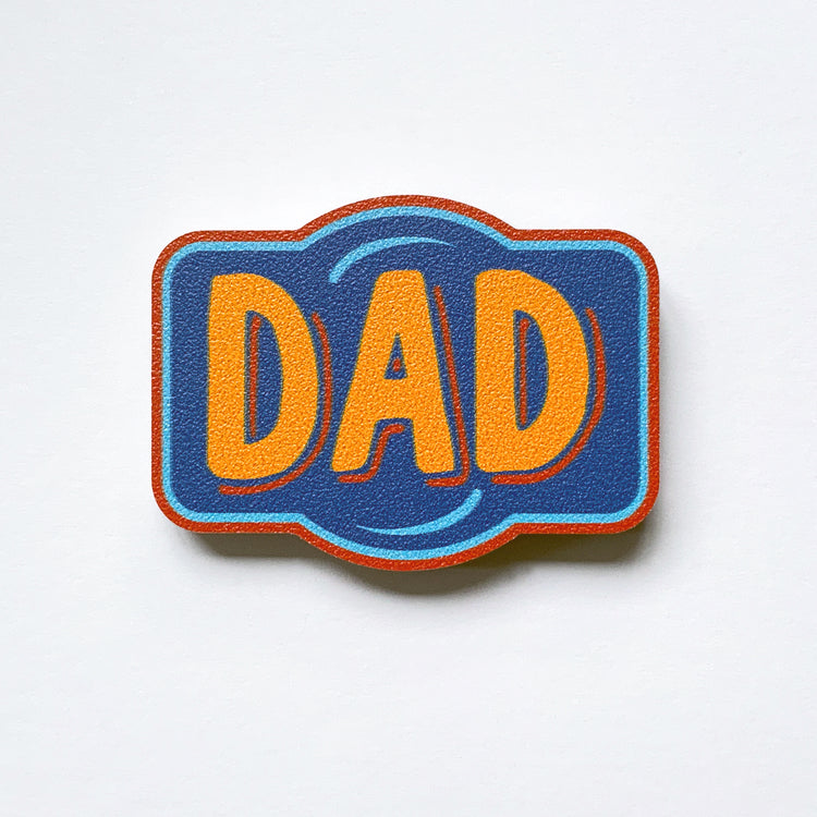 A vintage label shaped plywood fridge magnet by Beyond the Fridge with type that says dad