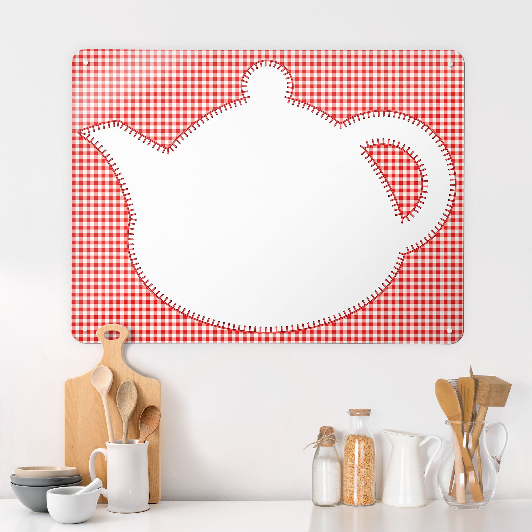 A  kitchen interior with a magnetic metal wall art panel showing an appliqué teapot design in white on a red gingham background