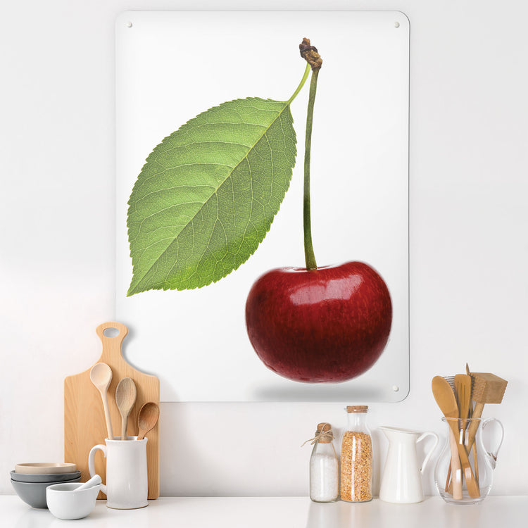 A kitchen interior with a magnetic metal wall art panel showing a photograph of a red cherry on a white background