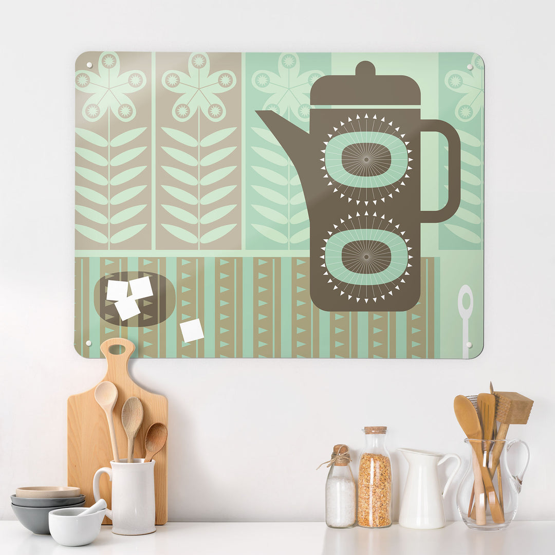 A kitchen interior with a magnetic metal wall art panel showing a retro coffee pot design in neutral tones of green and brown