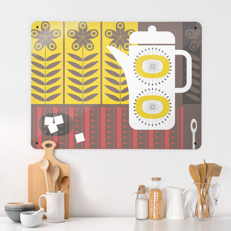 A kitchen interior with a magnetic metal wall art panel showing a retro coffee pot design in white, yellow, red and brown