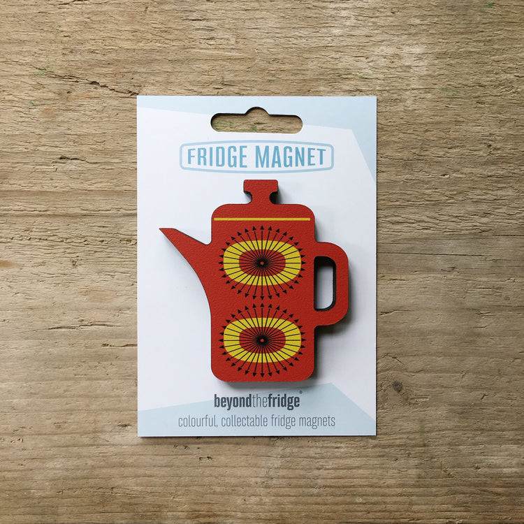 A red coffee pot shaped plywood fridge magnet by Beyond the Fridge in it’s pack on a wooden background