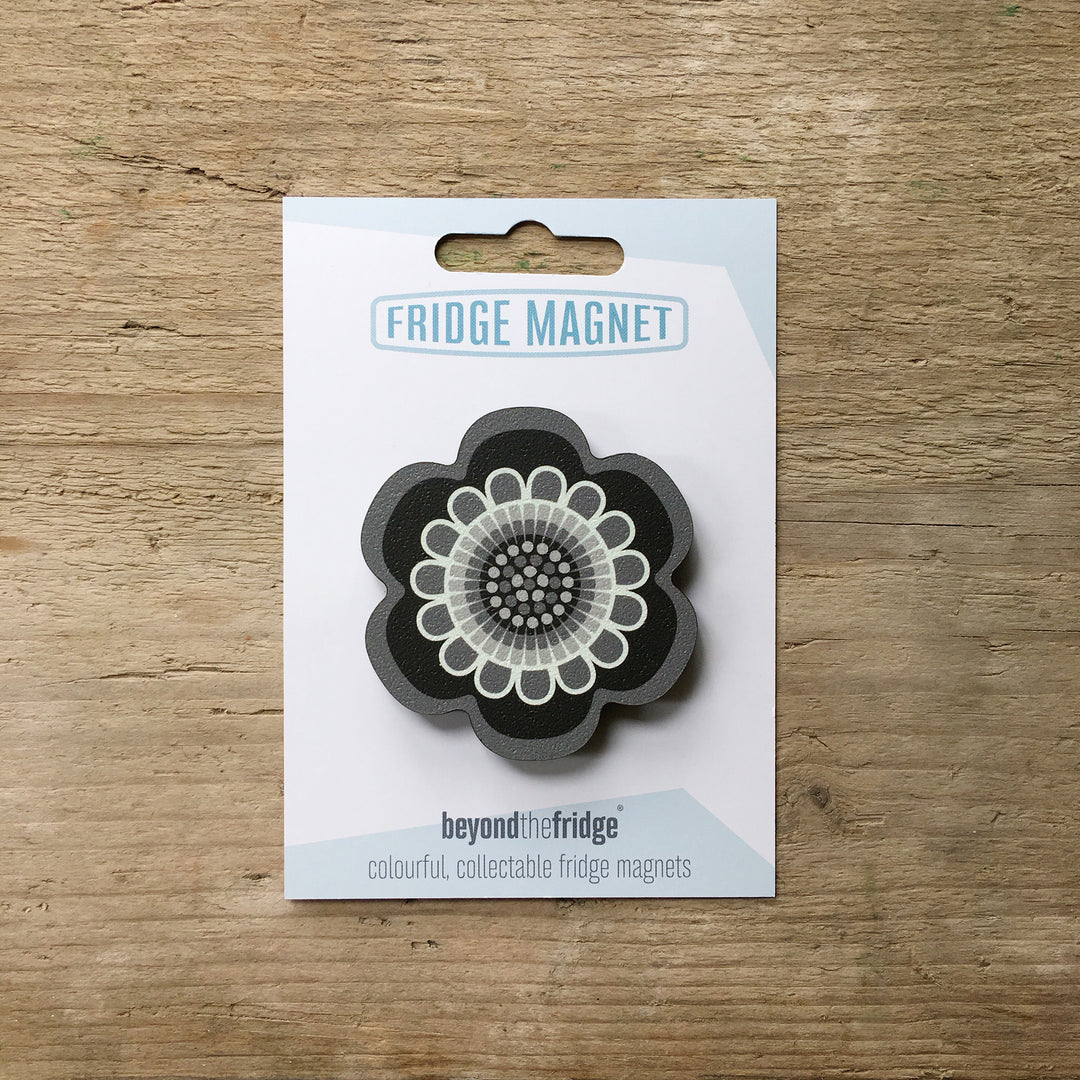 A black and white flower design plywood fridge magnet by Beyond the Fridge in it’s pack on a wooden background