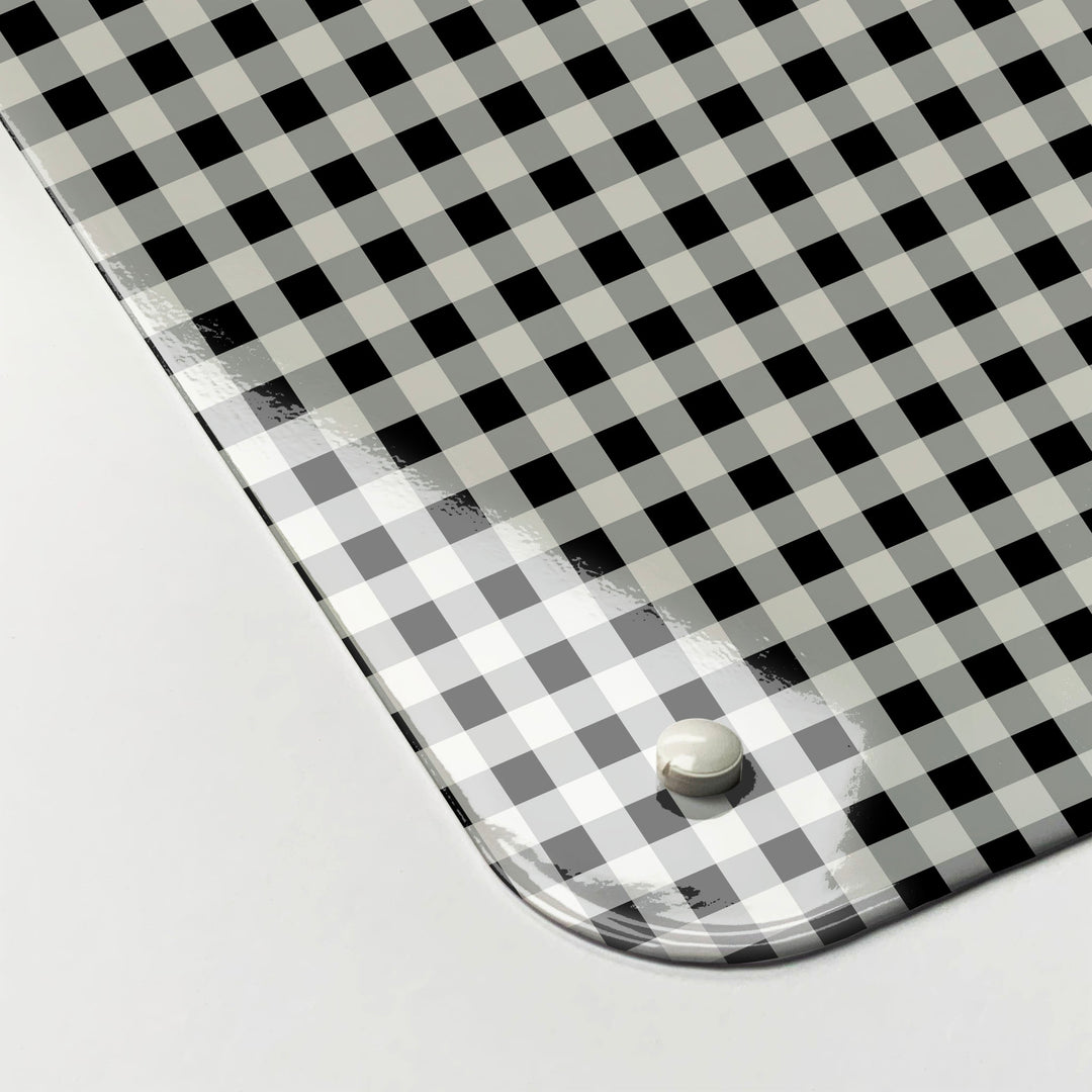 The corner detail of a black and white gingham design magnetic board to show it’s high gloss surface