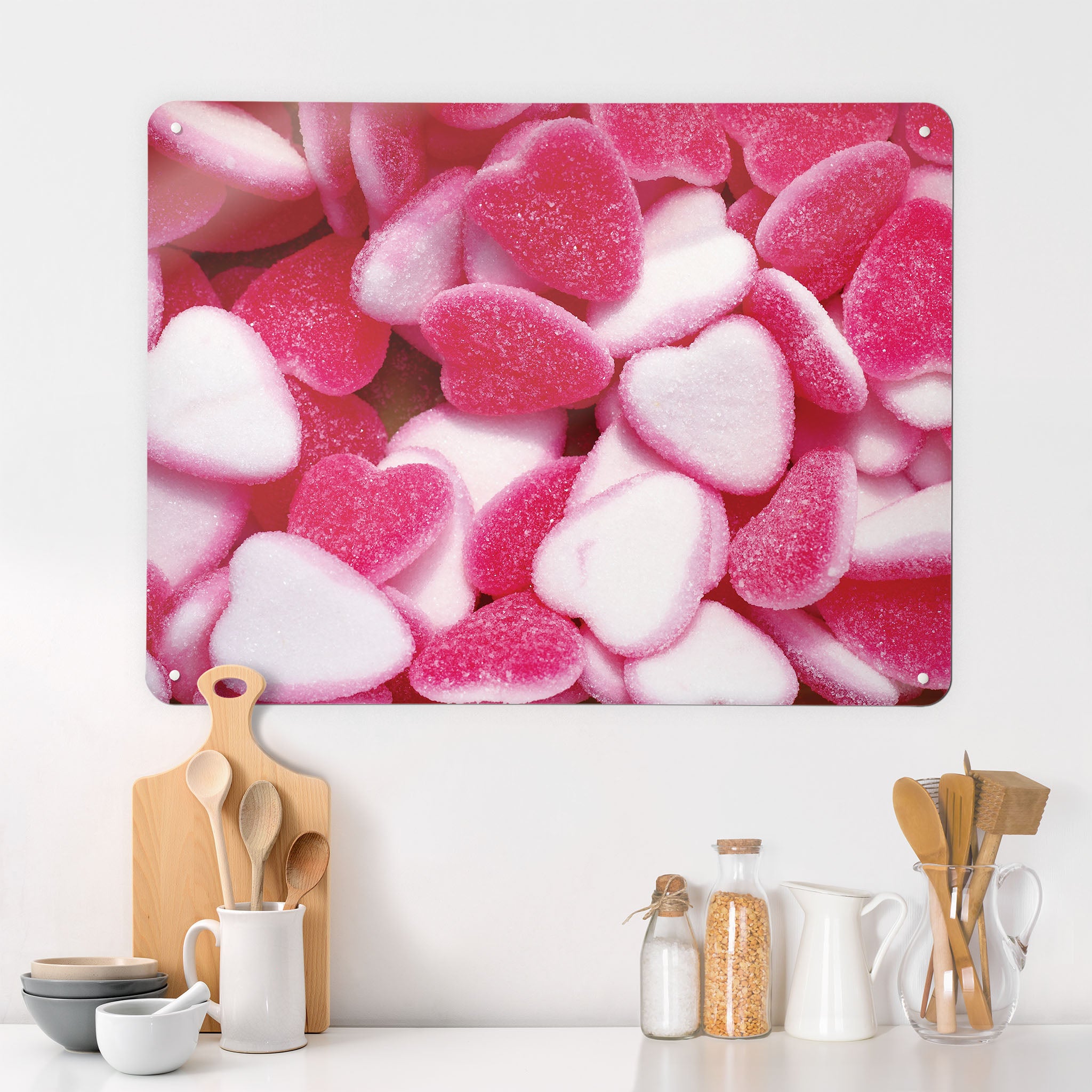 A desk in a kitchen interior with a magnetic metal wall art panel showing a photograph of pink heart shaped candy
