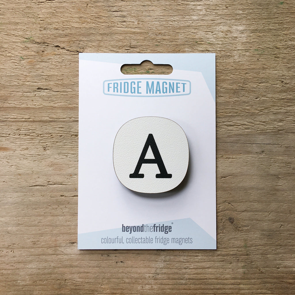 A letter A alphabet design plywood fridge magnet by Beyond the Fridge in it’s pack on a wooden background