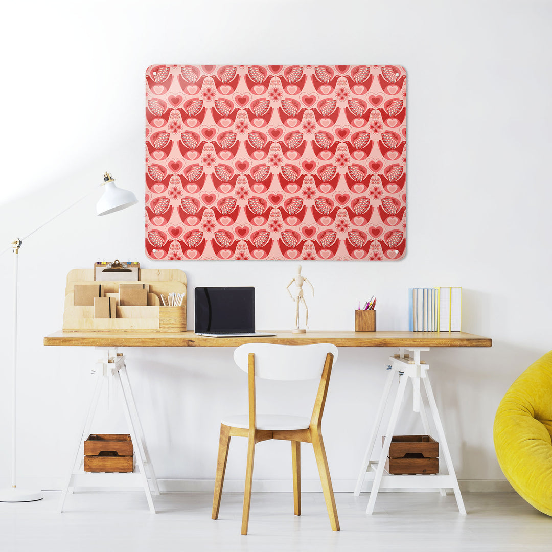 A desk in a workspace setting in a white interior with a magnetic metal wall art panel showing a retro love bird design
