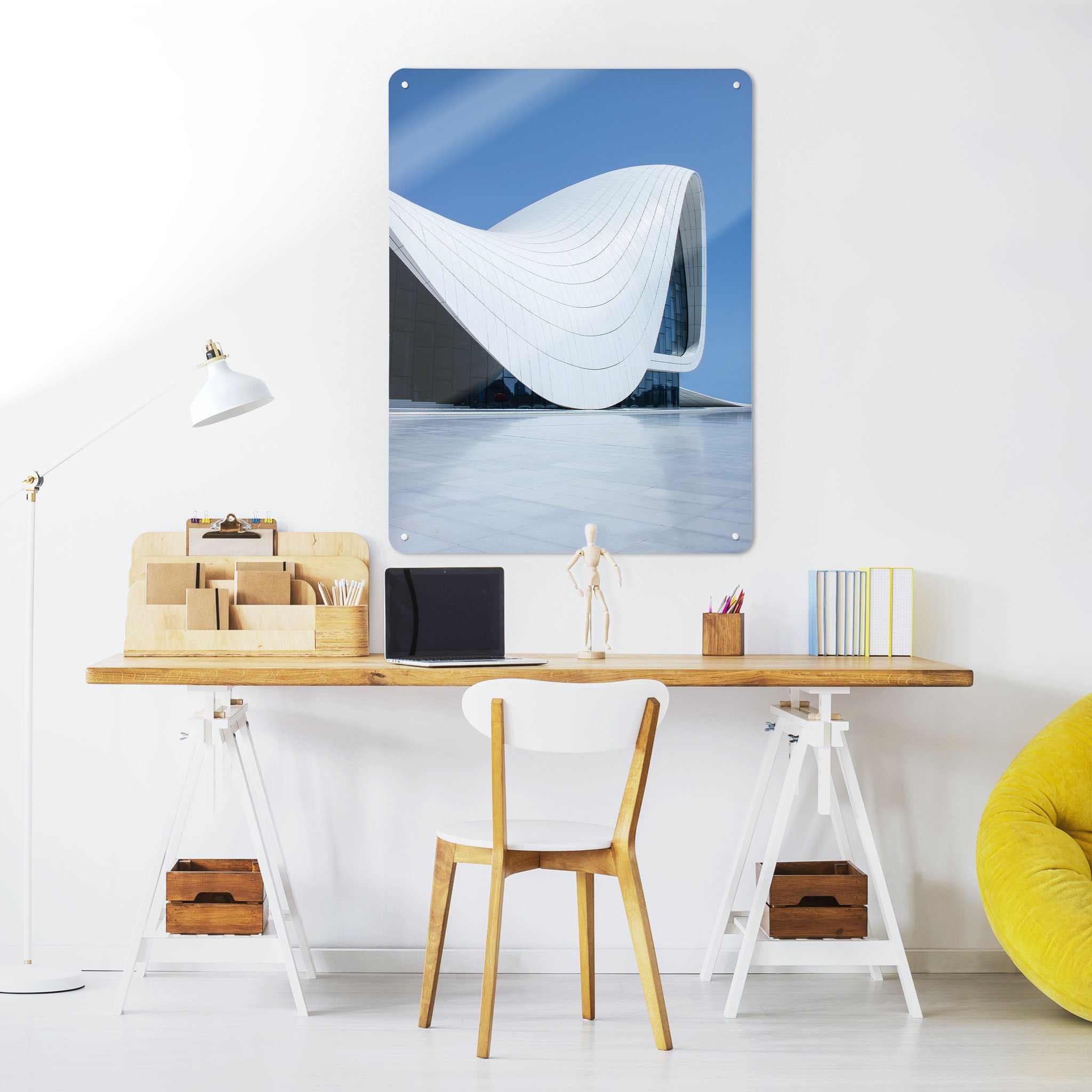 A desk in a workspace setting in a white interior with a magnetic metal wall art panel showing the Heydar Aliyev Centre