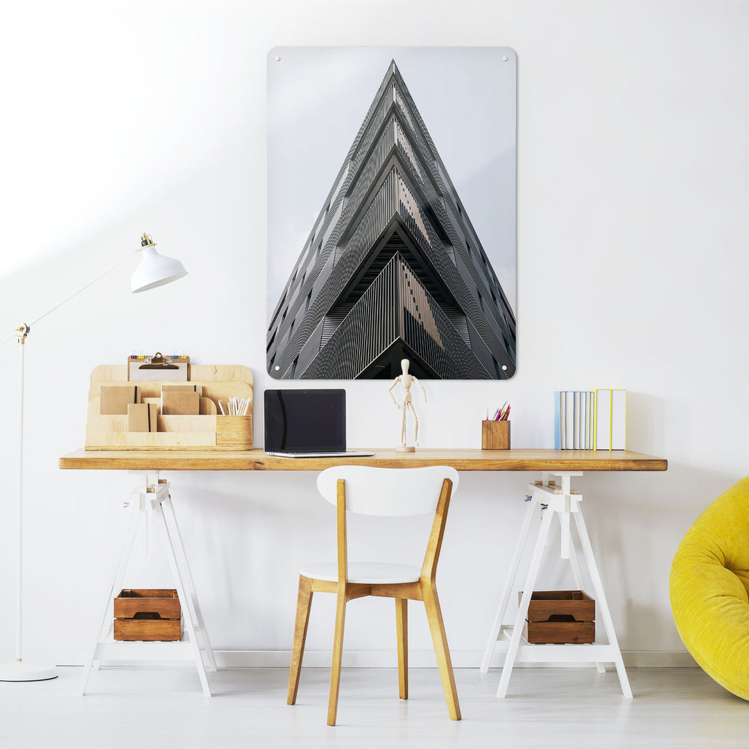 A desk in a workspace setting in a white interior with a magnetic metal wall art panel showing a black and white photograph of a London Skyscraper