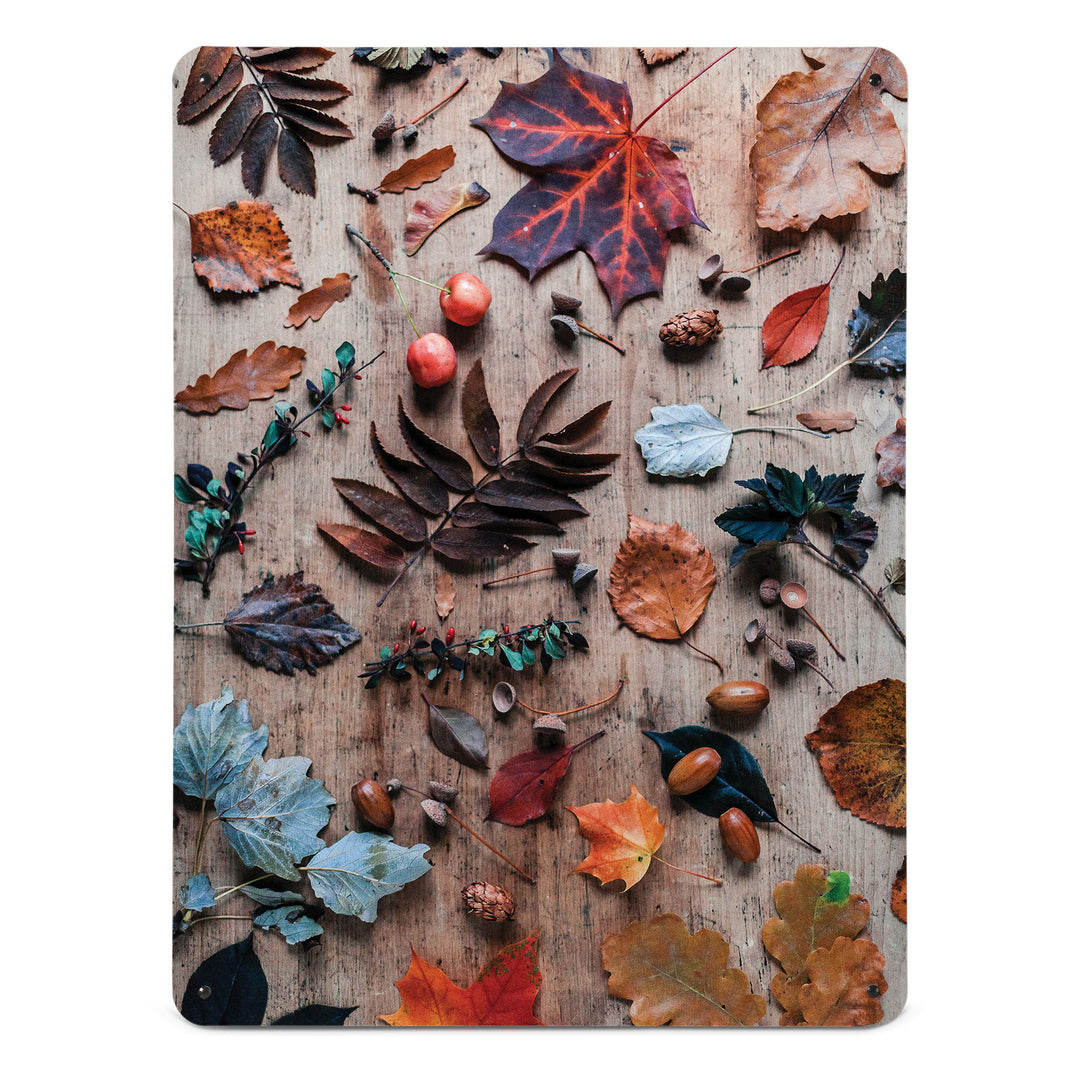 A large magnetic notice board by Beyond the Fridge with a photograph of a flatlay of autumn leaves and acorns on a wooden background
