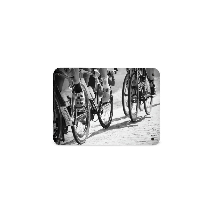 A small magnetic notice board by Beyond the Fridge with a black and white image of cyclists focusing on the wheels of the bikes
