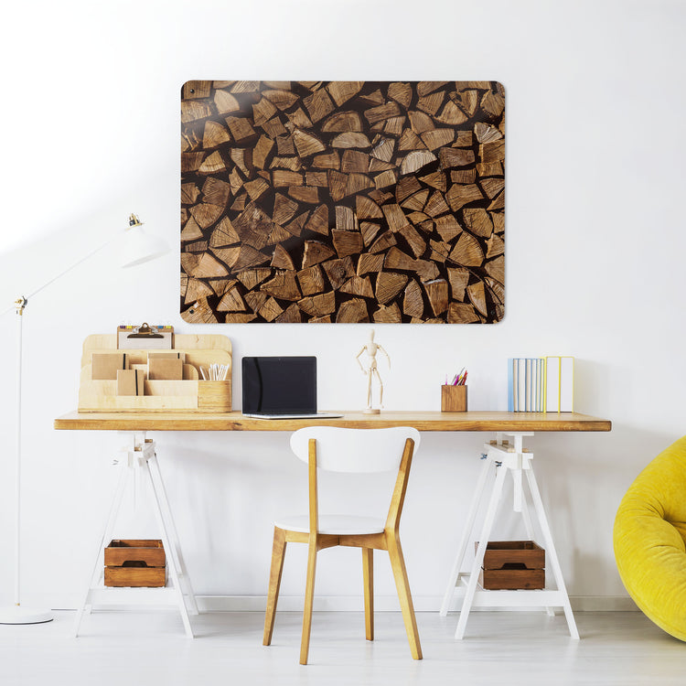 A desk in a workspace setting in a white interior with a magnetic metal wall art panel showing a photograph of a pile of logs
