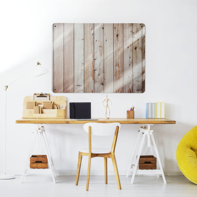 A desk in a workspace setting in a white interior with a magnetic metal wall art panel showing a photograph of wooden cladding