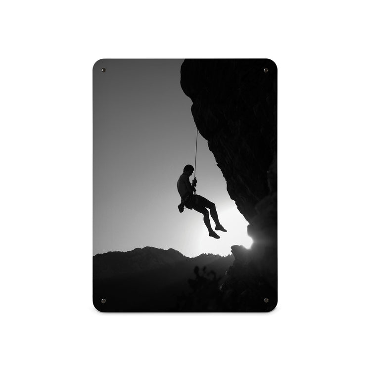 A medium magnetic notice board by Beyond the Fridge with a black and white photographic image of a rock climber suspended on a cliff in silhouette 