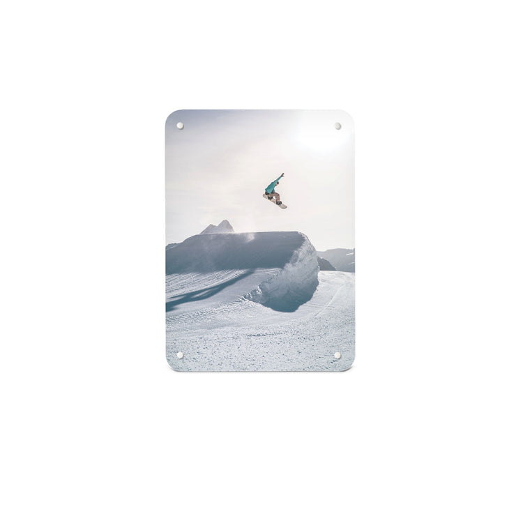 A small magnetic notice board by Beyond the Fridge with a photograph of a snowboarder jumping on a snowboard in a bright snowy landscape