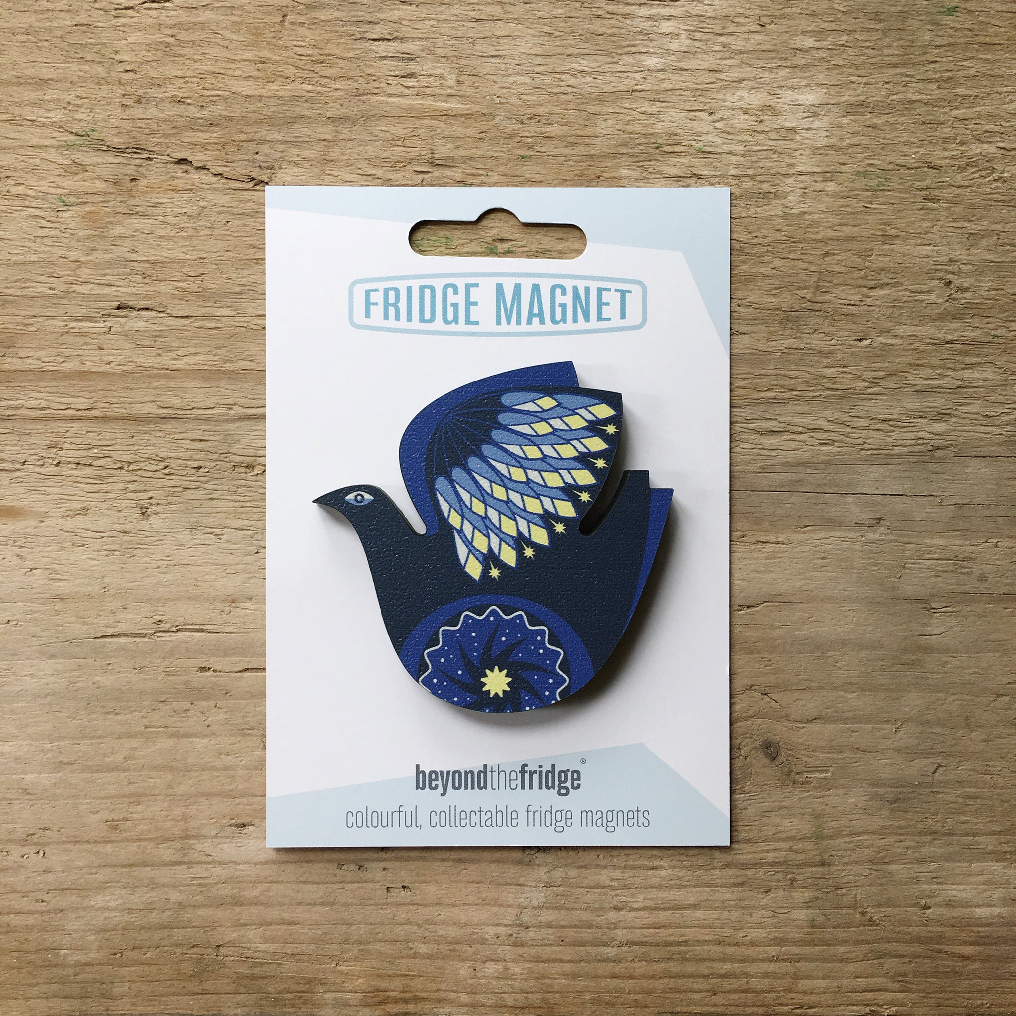 A retro night bird design plywood fridge magnet by Beyond the Fridge in it’s pack on a wooden background