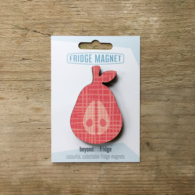 A pink coral pear design plywood fridge magnet by Beyond the Fridge in it’s pack on a wooden background