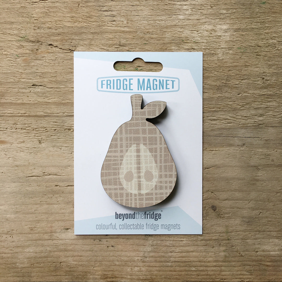 A grey pear design plywood fridge magnet by Beyond the Fridge in it’s pack on a wooden background