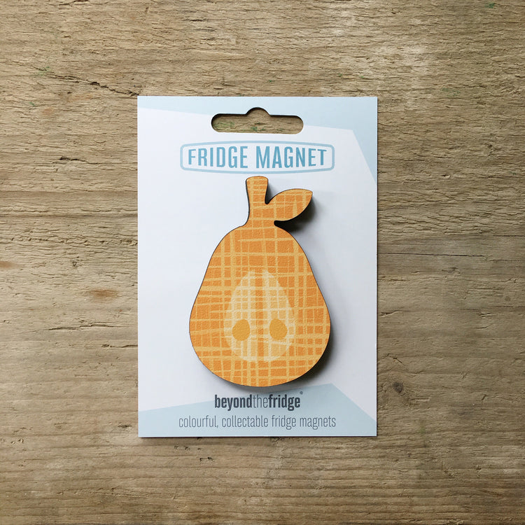 An orange pear design plywood fridge magnet by Beyond the Fridge in it’s pack on a wooden background