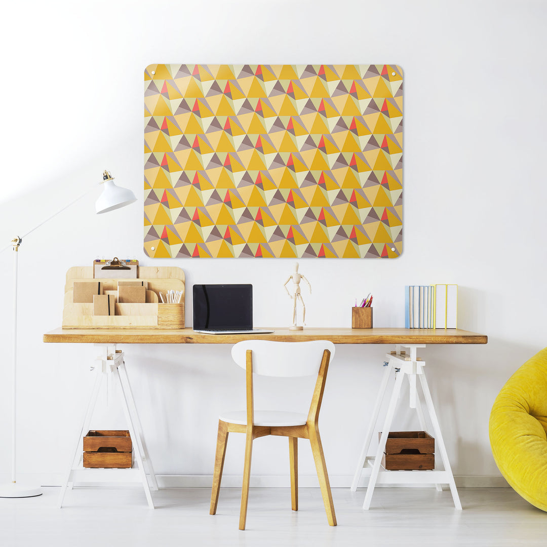 A desk in a workspace setting in a white interior with a magnetic metal wall art panel showing a shards design in summer colour way