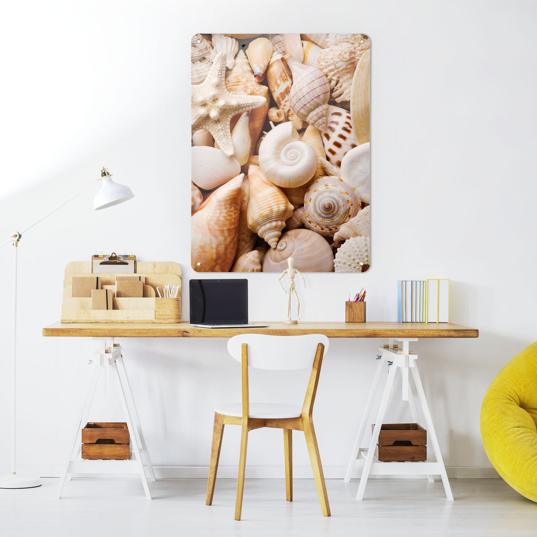 A desk in a workspace setting in a white interior with a magnetic metal wall art panel showing a shells photograph