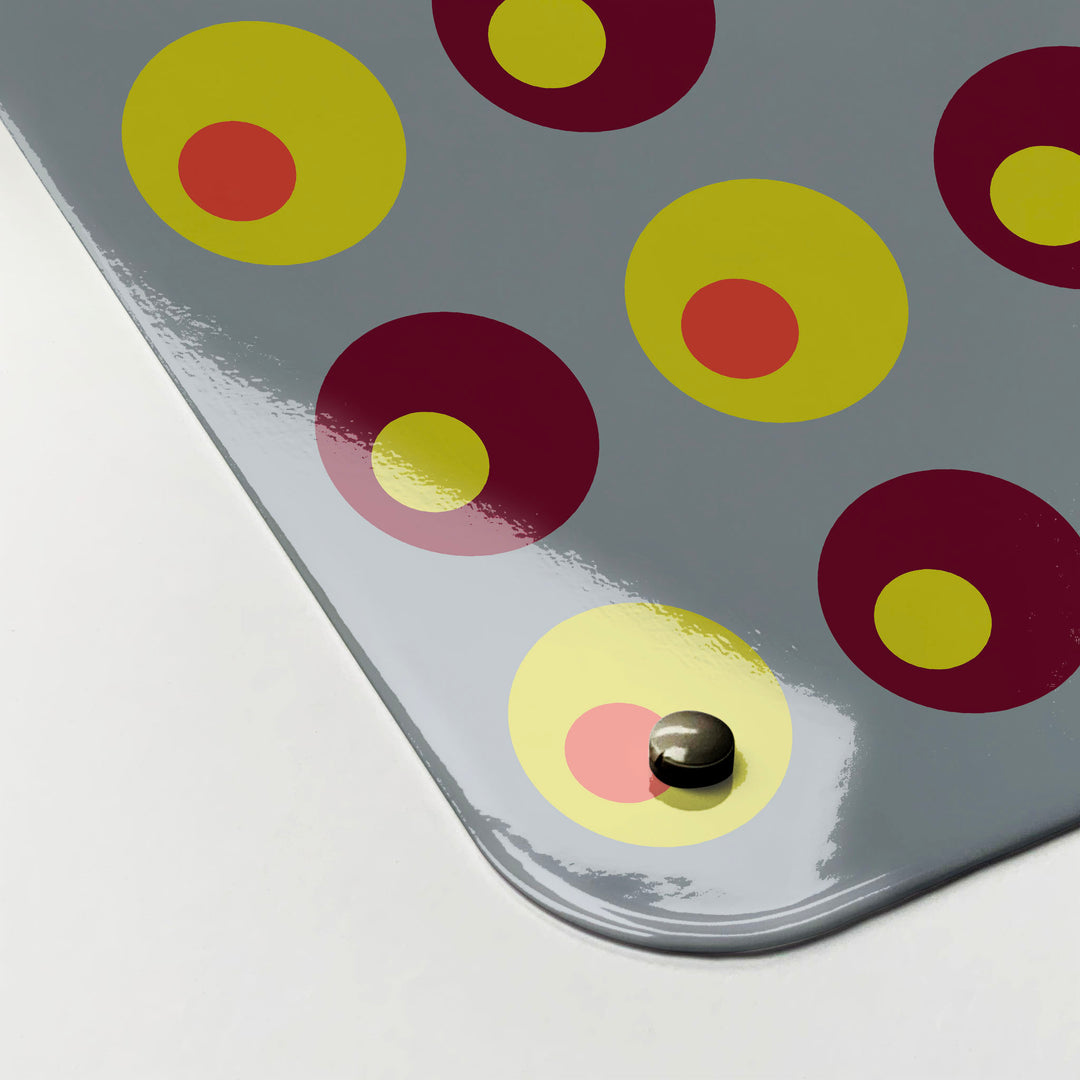 The corner detail of a spots design in yellow, orange and maroon colours magnetic board to show it’s high gloss surface