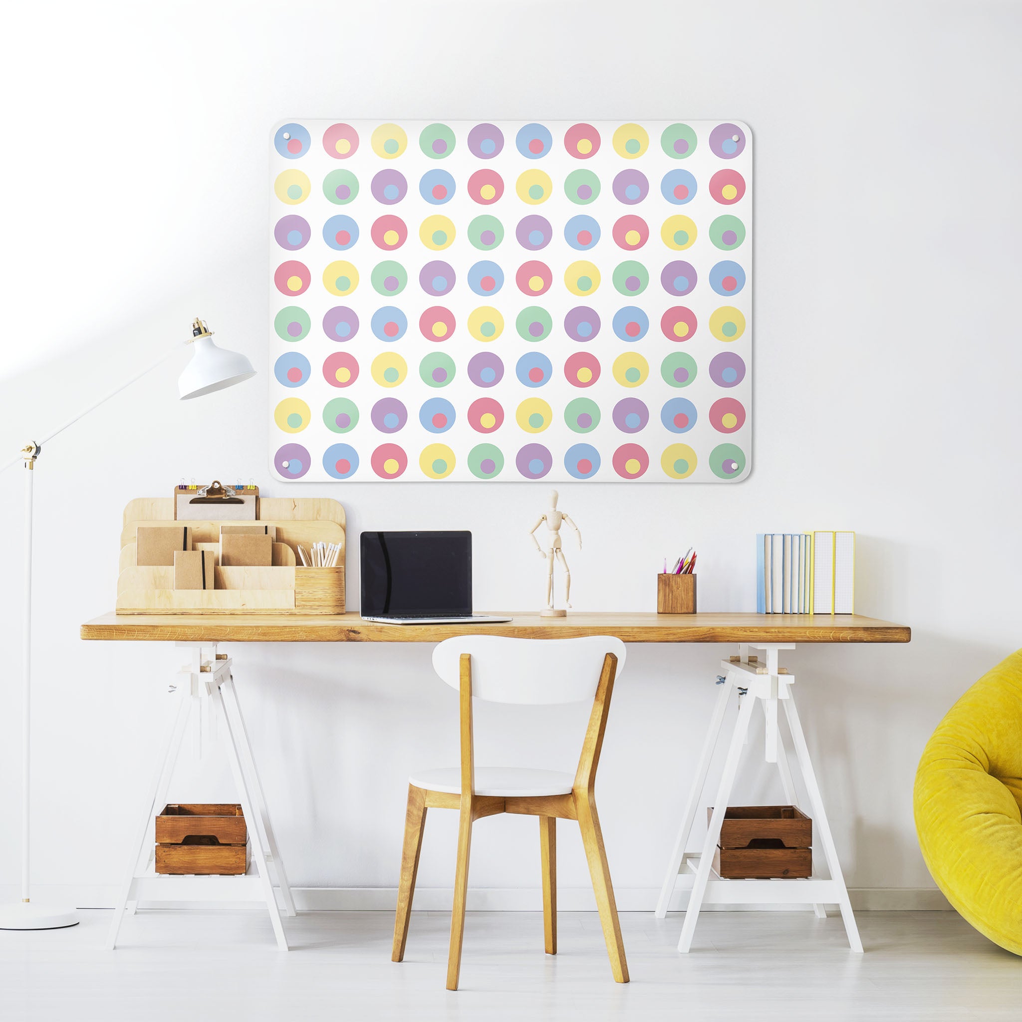 A desk in a workspace setting in a white interior with a magnetic metal wall art panel showing a spots on white design